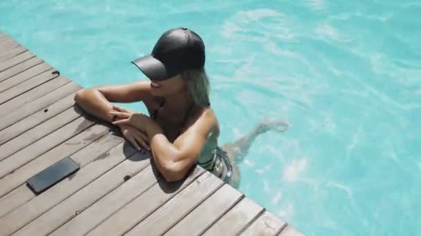 Hermosa mujer en sombrero negro es relajante en la piscina — Vídeos de Stock