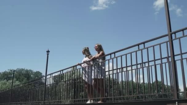 Жінки стоять на мосту. Блакитне небо на фоні — стокове відео