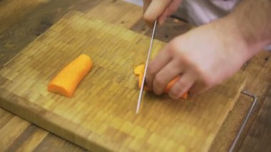 Şef ahşap kesme tahtası üzerinde taze havuç kesiyor