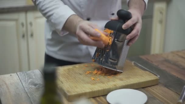 El cocinero frota zanahorias en un rallador — Vídeos de Stock