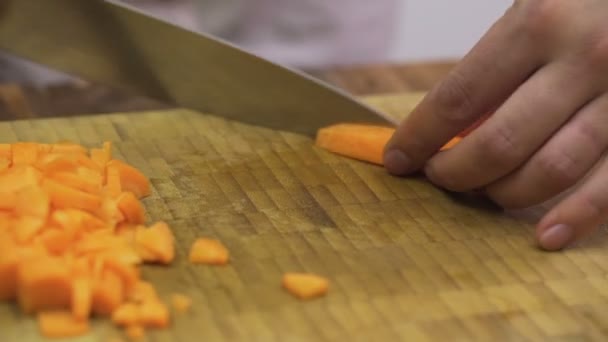Манская рука режет свежую морковь на деревянной разделочной доске — стоковое видео