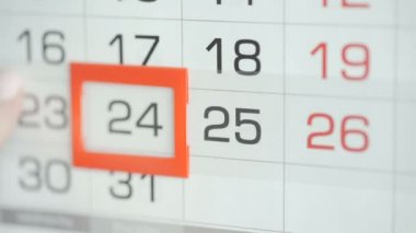 Ofisteki kadınlar duvar takvimindeki tarihi değiştirirler. Değişiklikler 24 ile 25 arasında