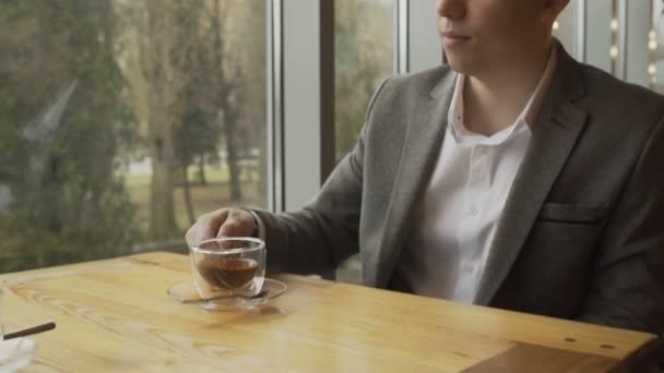 Ein Mann in einem Café trinkt grünen Tee — Stockvideo