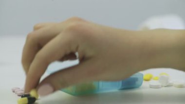 Kadın kapsülleri bir kutuya koyar.