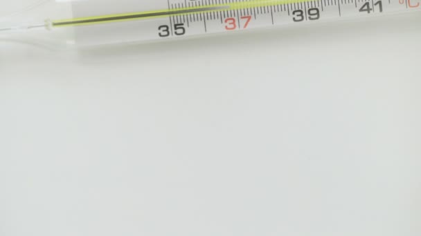 Vetro termometro mercuriale prende temperatura su sfondo bianco — Video Stock