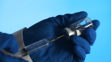 Şırıngayı kullanan doktor, ilacı cam şişede karıştırıyor.