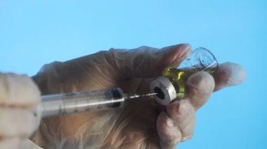 Mavi arka planda ampulden şırıngaya ilaç dolduruluyor