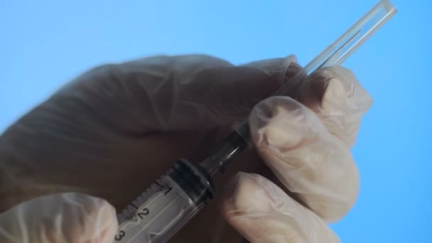Доктор в латексних рукавичках тримає шприц і відкриту голку — стокове відео