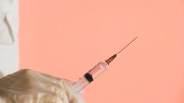 Doktor açık iğne ve pembe arka planda serpiştirilmiş ilaçlar