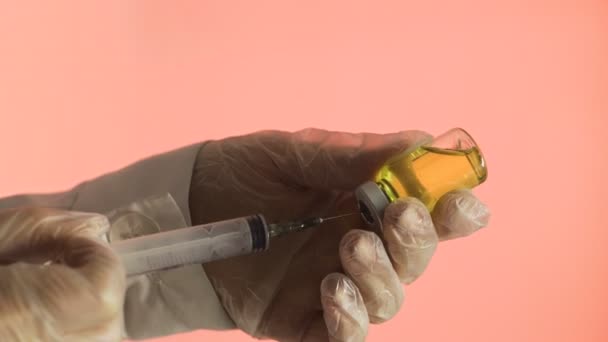 Filling medicine from ampule into syringe a yellow medicine on a pink background — Stock Video