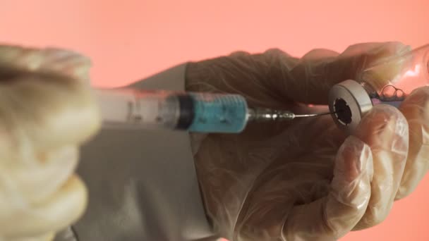 Filling medicine from ampule into syringe a blue medicine on a pink background — Stock Video