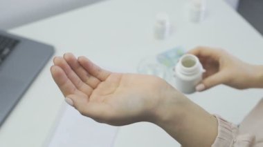 Kadın elindeki şişeden hapları döküyor. .