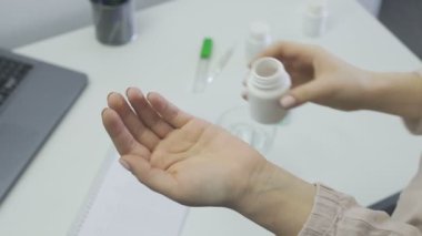 Kadın hap alır ve ilaç şişesinden aldığı vitaminleri ya da hapları gösterir.