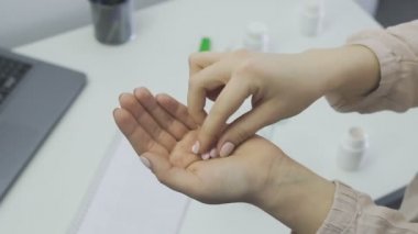 Bir sürü küçük ve pembe hap tutan genç bir kadın, ağzına bir hap alıyor.