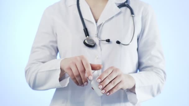 Doktorn häller ut en gul tablett ur flaskan på en blå bakgrund — Stockvideo