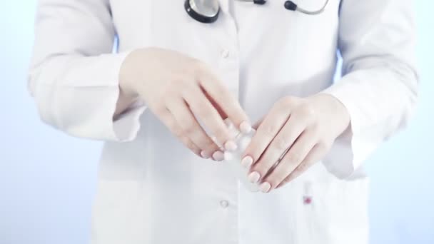Dokter giet een gele pillen uit de fles op een blauwe achtergrond — Stockvideo
