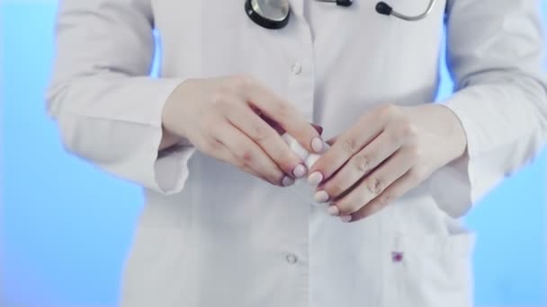 Doktorn häller ut en gul tablett ur flaskan på en blå bakgrund — Stockvideo