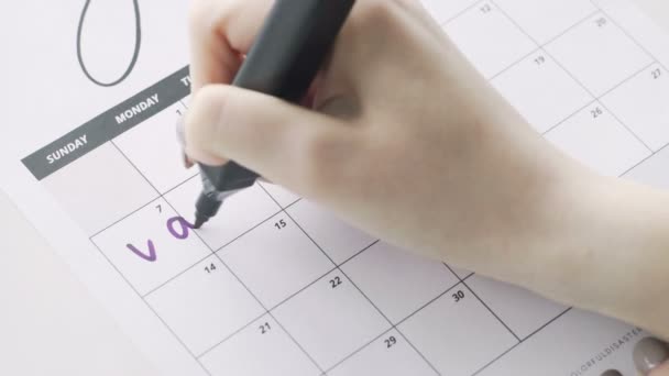 Womans mão escrevendo com Violet caneta feltro em férias palavra calendário — Vídeo de Stock