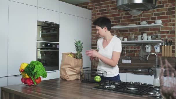 Ama de casa en la cocina con una bolsa de frutas — Vídeo de stock