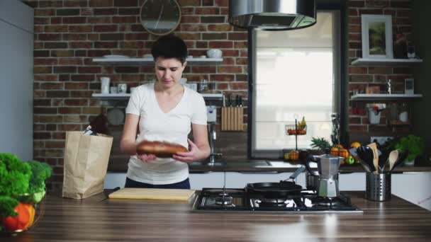 Домохозяйка приходит на белую кухню с сумкой — стоковое видео