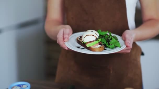 Mujer sosteniendo una bruschetta con aguacate, huevo hirviendo, salmón y requesón — Vídeos de Stock