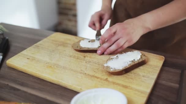 Mujer esparciendo queso sobre pan tostado seco de centeno con un cuchillo. — Vídeo de stock