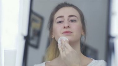 Aynada yüzünü temizlemek için pamuk yastık kullanmak kadının reflectoin.