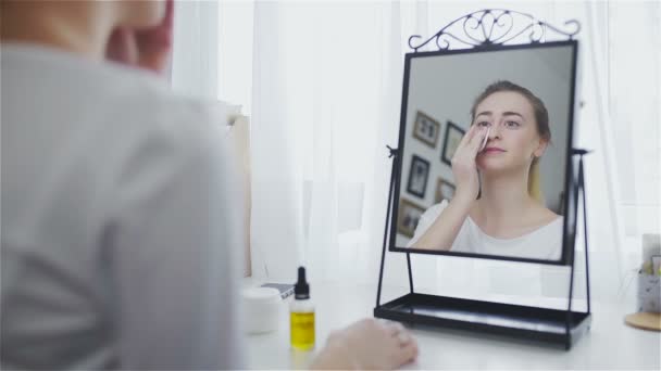 Γυναίκα καθαρισμού προσώπου με βαμβάκι μπροστά από τον καθρέφτη — Αρχείο Βίντεο