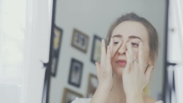 Hermosa joven aplicación de crema en la cara — Vídeo de stock