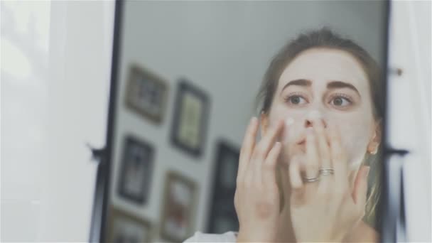 Femme appliquant masque crème hydratante pour la peau sur le visage — Video
