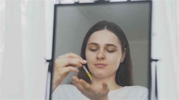Młoda kobieta, stosując balsam oleju na jej twarzy — Wideo stockowe