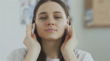 Güzel kadın temizlik pamuklu ped ile yüz ve kameraya bak