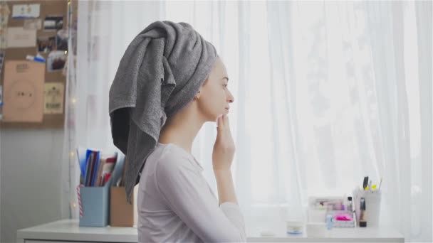 Egy fiatal nő tisztítja a bőrt az arc egy vattát, a szobában — Stock videók