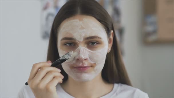 Mulher usar escova para aplicar máscara cosmética na sala e olhar para a câmera — Vídeo de Stock