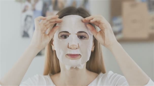 Bella ragazza togliere maschera tessuto idratante nello specchio anteriore — Video Stock