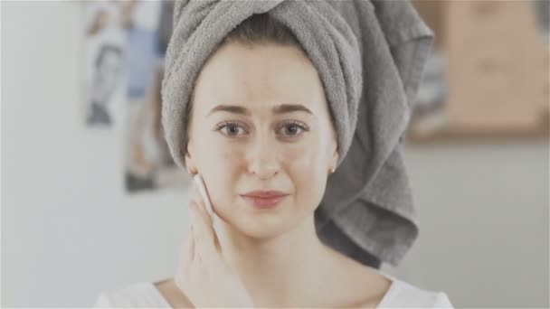 Woman with towel on head cleanses the skin of the face with a cotton pad — Stock Video