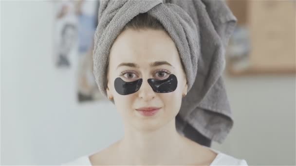 女性の頭の上のタオルを脱いでコラーゲン保湿マスクのパッチ. — ストック動画