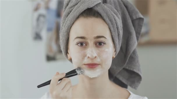 Belle femme avec serviette sur la tête utiliser brosse pour appliquer un masque cosmétique — Video