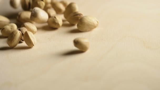 Sabrosos pistachos están rodando sobre una mesa de madera — Vídeos de Stock