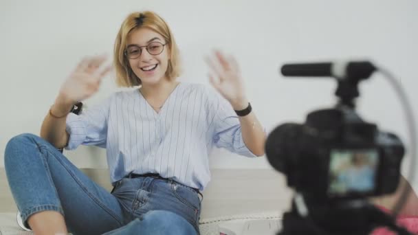 Young female blogger talking on camera and waving hello with her hand — Stock Video