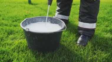Futbol sahasını işaretlemeye hazırlanın. Kovadaki matkapla beyaz boyayı karıştırma işlemi