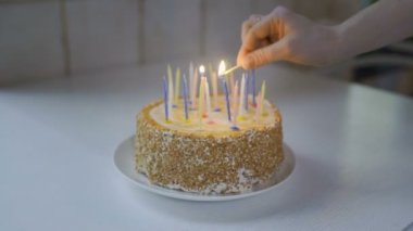 Doğum günü pastasındaki mumları yakıyorum.