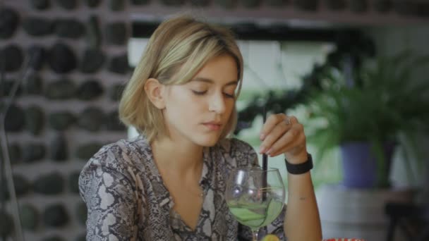Mujer joven triste y deprimida sentada en la cafetería y bebiendo cóctel — Vídeo de stock