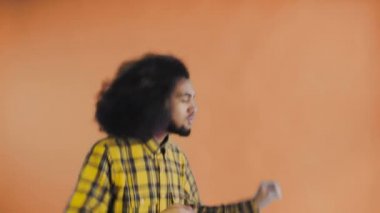 Portakal rengi arka planda dans eden gülümseyen genç Afrikalı adam. Duyguların kavramı