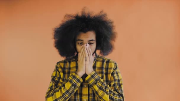 Triste hombre afro-americano sintiéndose molesto en el fondo naranja mirando cámara. Concepto de emociones — Vídeo de stock