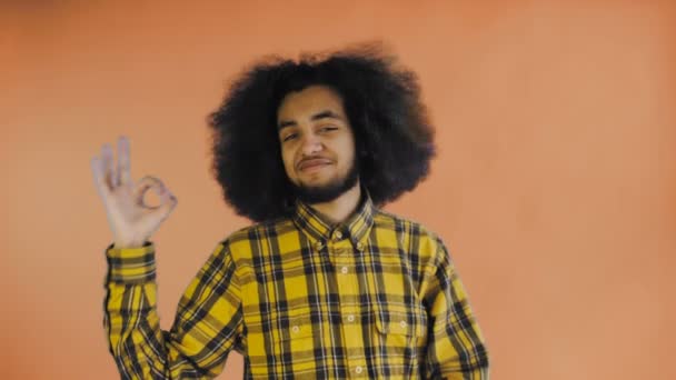 Sonriente chico afro-americano atractivo mostrando gesto aceptable mientras que de pie aislado sobre fondo naranja. Concepto de emociones — Vídeo de stock