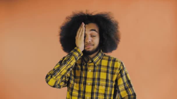 Maschio afro-americano deluso che fa il gesto del facepalm sullo sfondo arancione. Concetto di emozioni — Video Stock