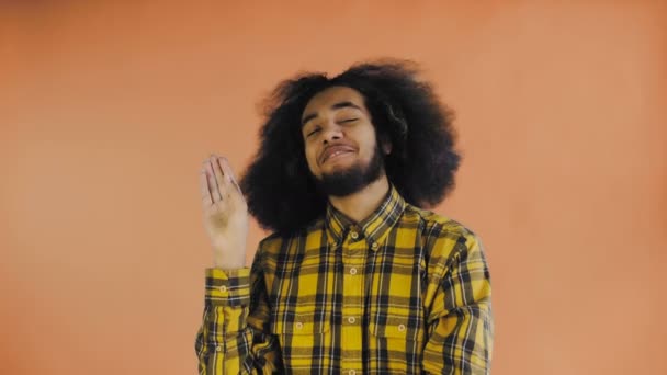 Young Afro-American man showing silence or bla bla gesture on Orange background. Concept of emotions — Stock Video