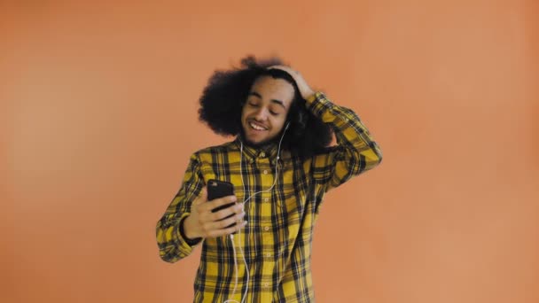 Jonge Afro-Amerikaanse man die belt met een telefoon op Orange achtergrond. Concept van emoties — Stockvideo