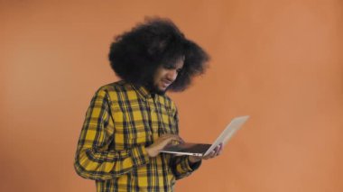 Laptopta yazan Afro-Amerikalı bir adam. Hayır, Sallanan Kafa tarafından. Turuncu arka planda. Duyguların kavramı